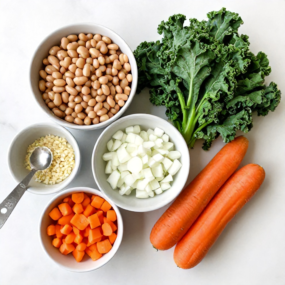 Overhead flat lay of raw ingredients for white bean and kale soup including white beans, kale, onions, garlic, and carrots