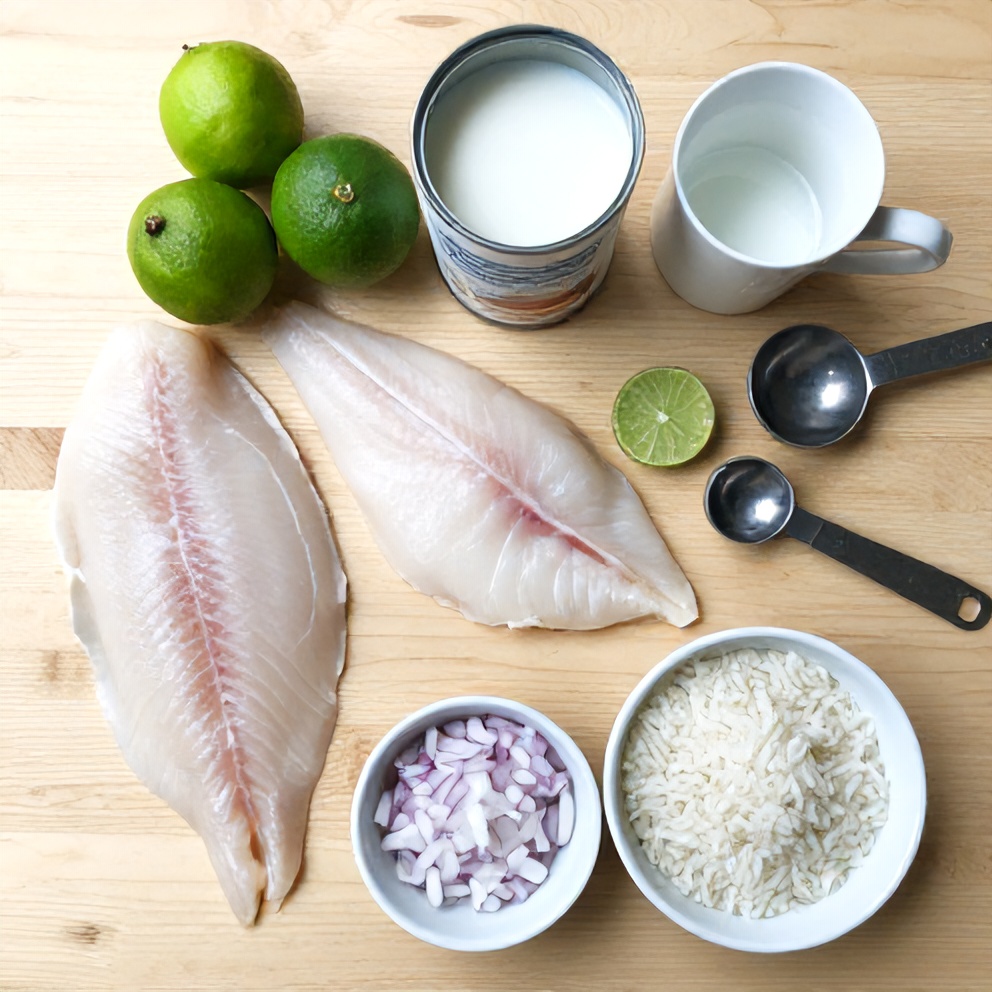 Overhead flat lay of raw ingredients including fresh fish, coconut milk, limes, jasmine rice, and spices