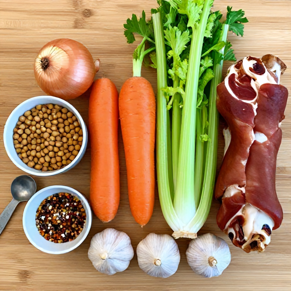 Split peas, onions, carrots, celery, and ham on a wooden surface